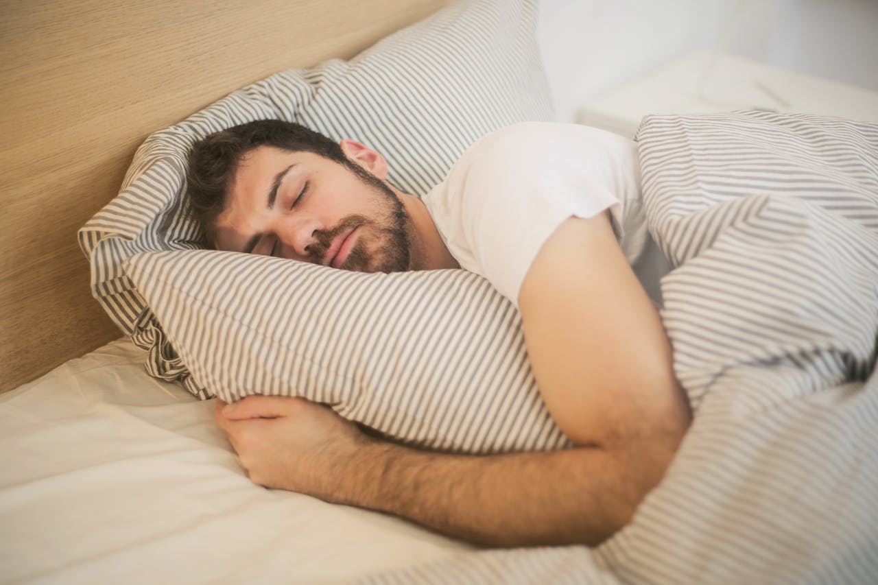 gallery-2 Man sleeping peacefully on striped bedding, embracing relaxation and comfort.